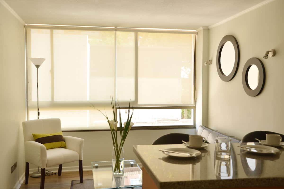 Un comedor moderno con una mesa de vidrio, sillas y un florero con plantas.