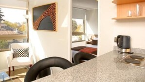 A compact kitchen with a granite countertop, a coffee maker, and a view of the adjacent living area.