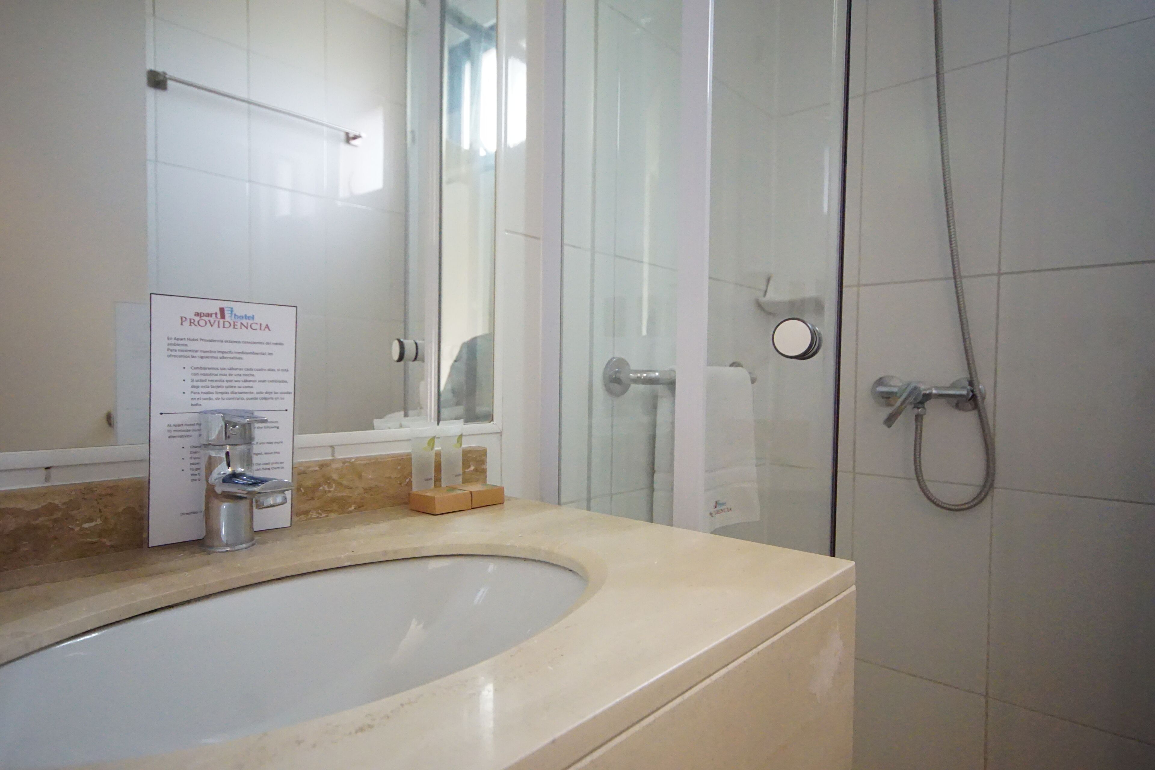 A bathroom with a sink, a glass shower enclosure, and a towel rack.