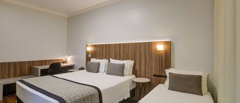 A hotel room with two beds, a desk, and a chair.