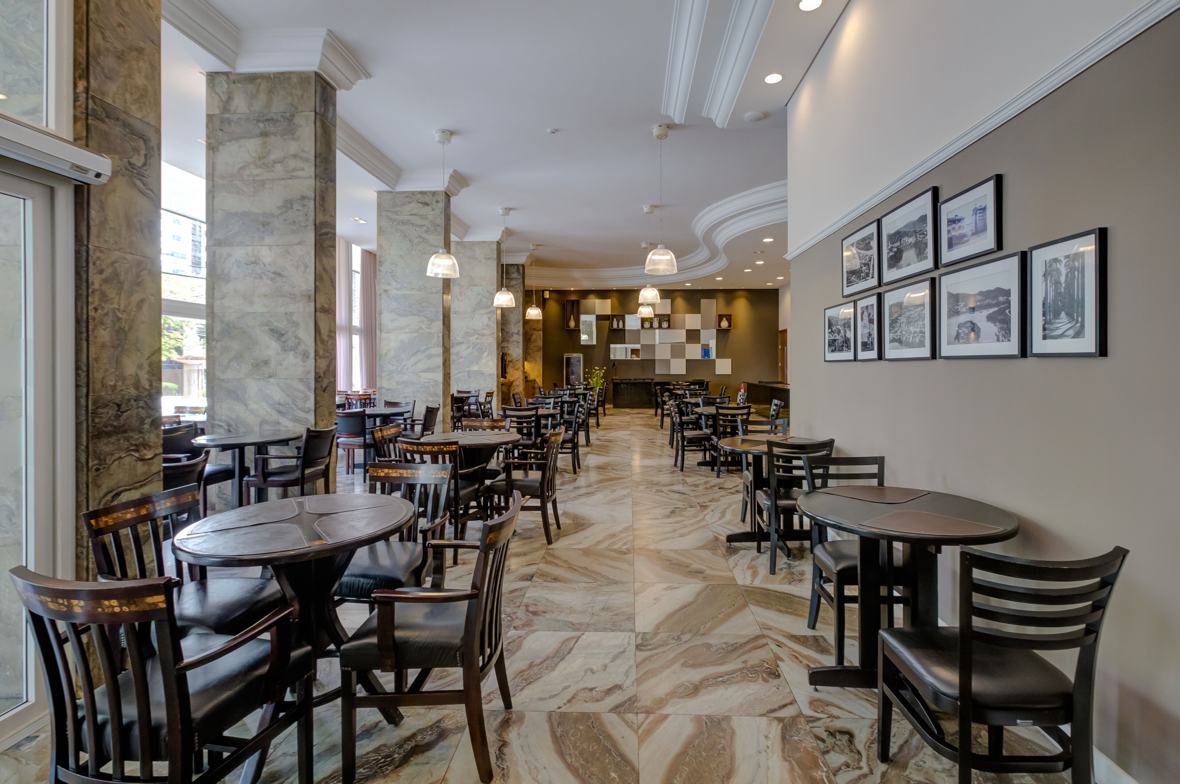A spacious indoor area with marble flooring, multiple tables and chairs, and framed pictures on the walls.