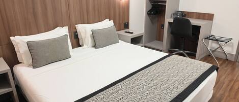 Una habitación de hotel moderna con una cama grande, un escritorio, una silla y un armario empotrado.