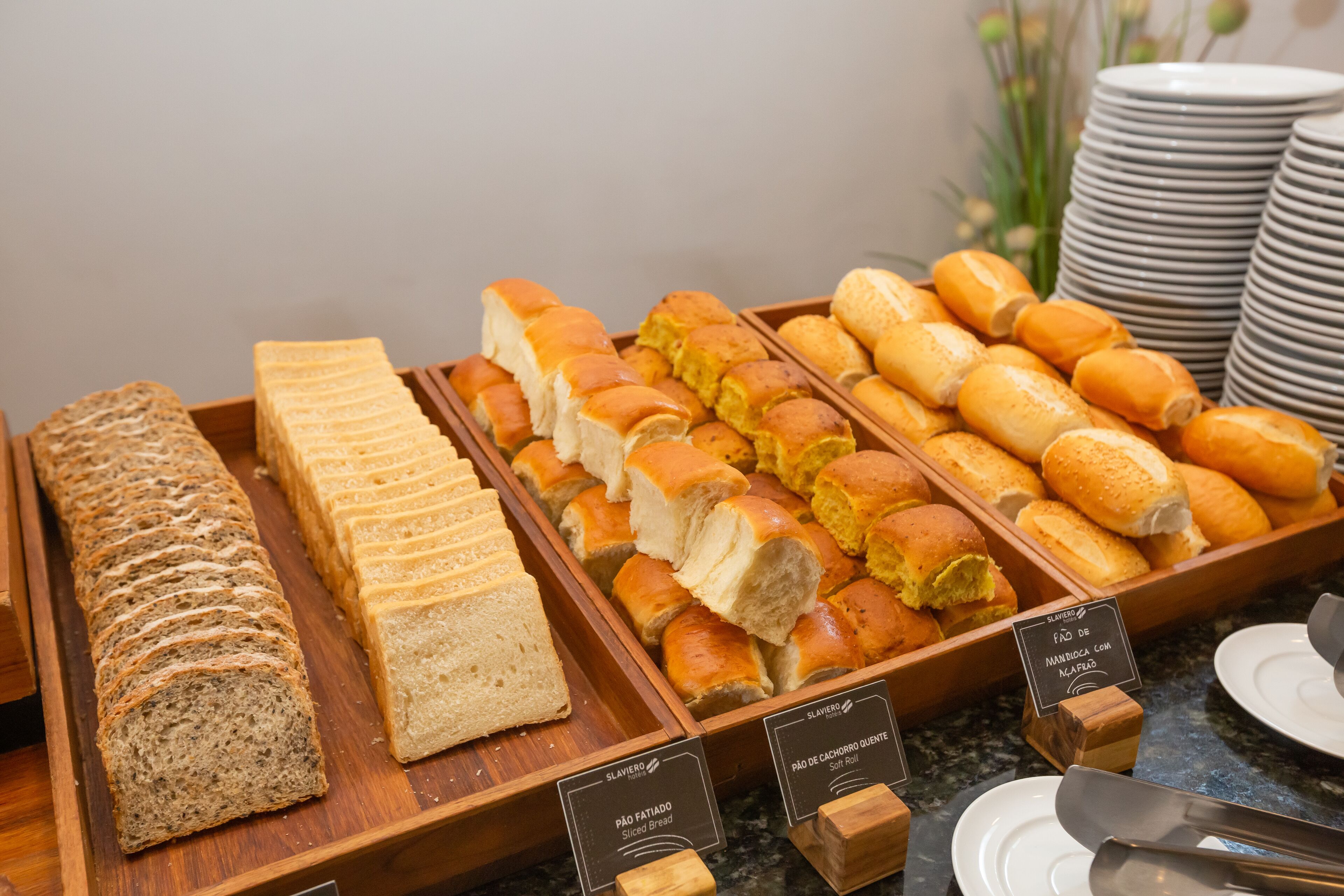 Variedad de panes y pasteles exhibidos en bandejas de madera.