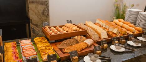 Un buffet proposant une variété d’aliments, notamment du pain, des pâtisseries et des en-cas.