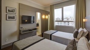 A hotel room with two beds, a TV, and a window with a city view. - SLAVIERO Blumenau (Blumenau)