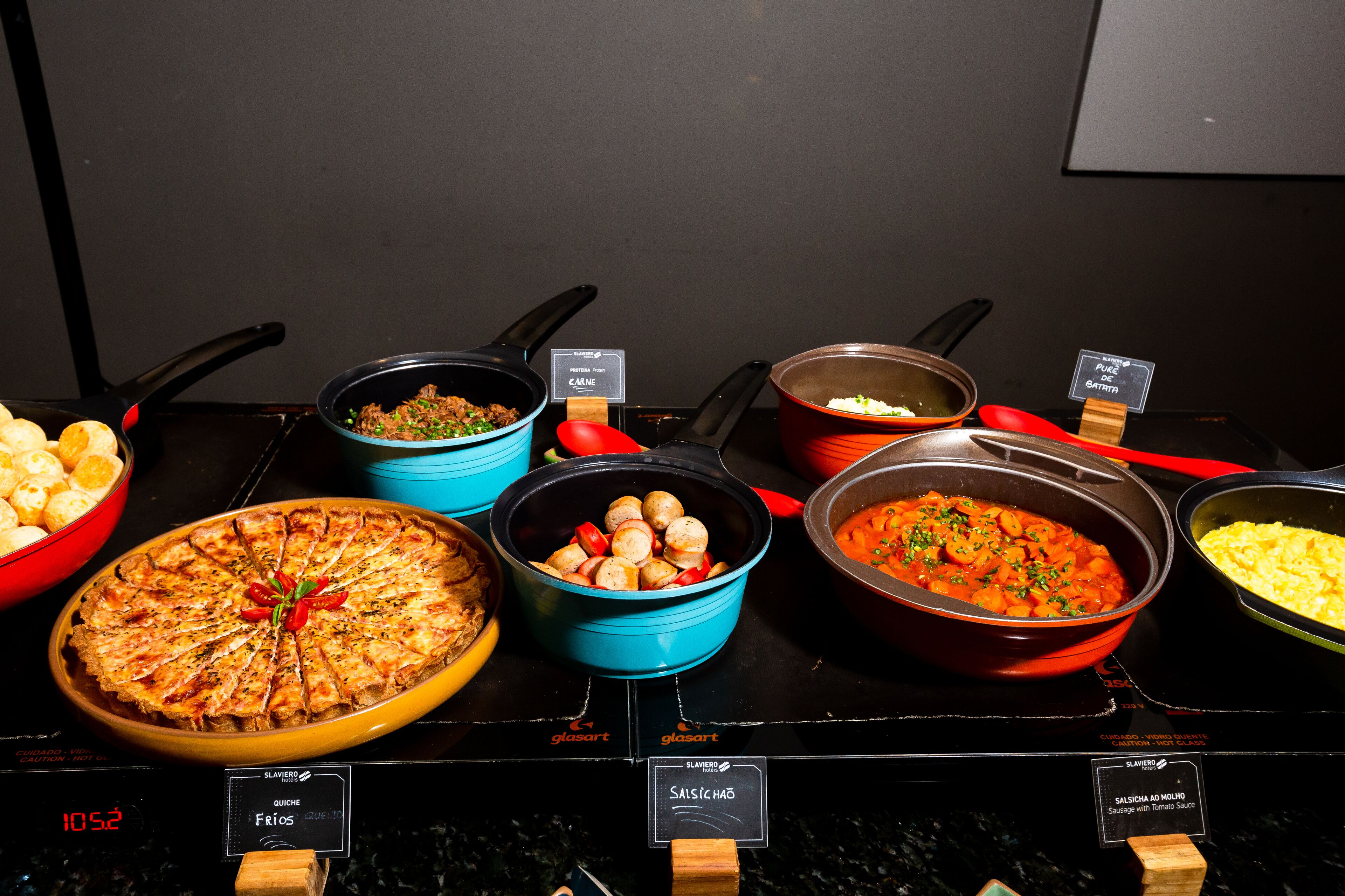 A buffet with various dishes including a pizza, a salad, and a pasta dish.