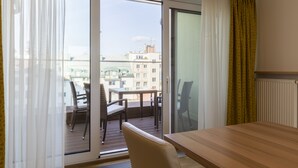 Un balcone con tavolo e sedie, una porta scorrevole in vetro e vista sugli edifici.