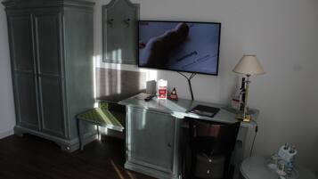 Een hotelkamer met een televisie, een bureau met lamp, een klein tafeltje met dienblad, een kast en een stoel.