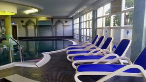 Een zwembadgedeelte met blauwe ligbedden en een glazen afscheiding.