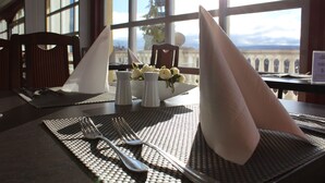 A dining table set with a placemat, a folded napkin, a fork, a knife, and a spoon. There is a salt and pepper set on the table.