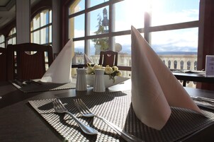 Una mesa de comedor dispuesta con un mantel individual, un servilleta doblada, un tenedor, un cuchillo y una cuchara. Hay un salero y un pimentero sobre la mesa.