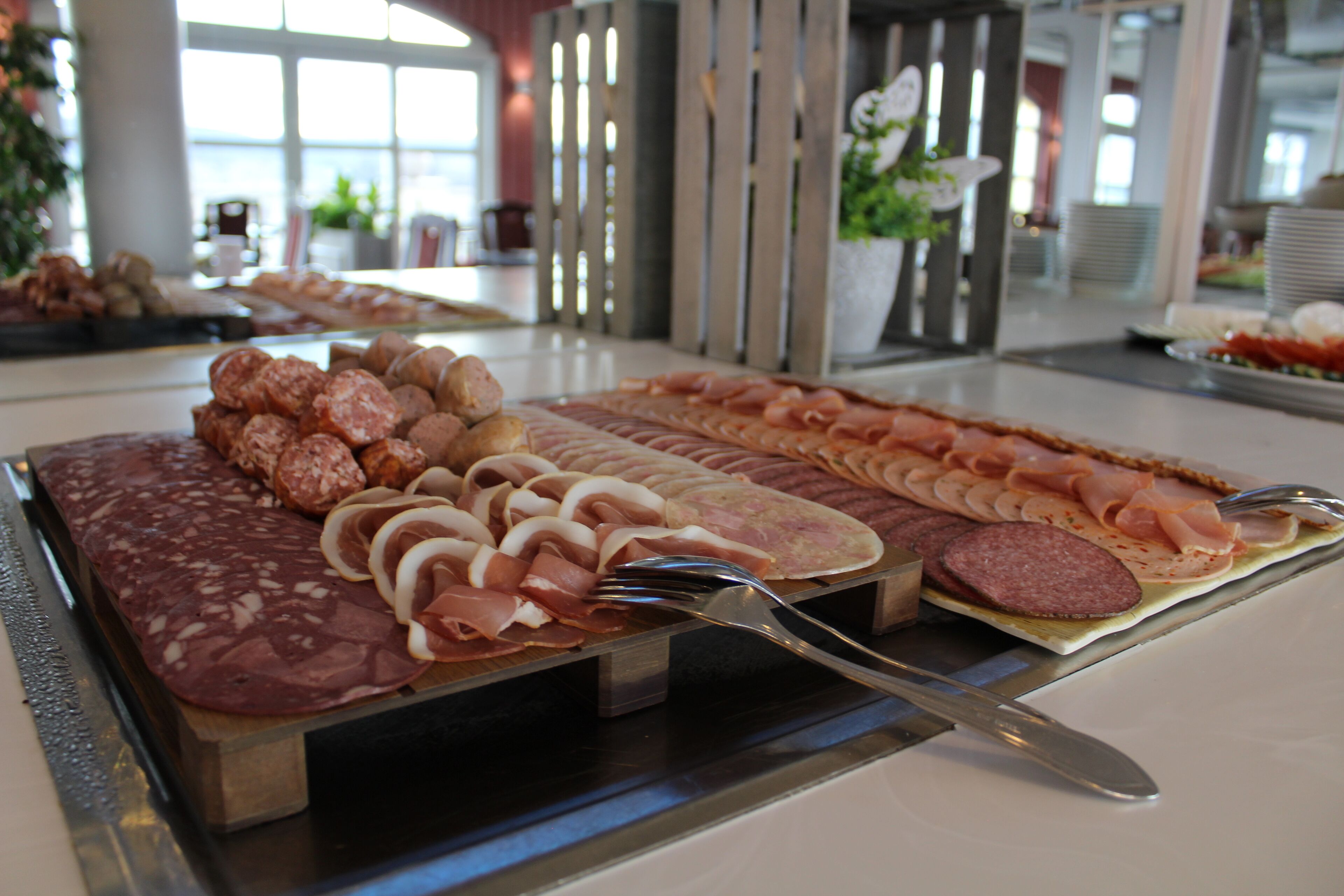 A buffet with various meats and cheeses.