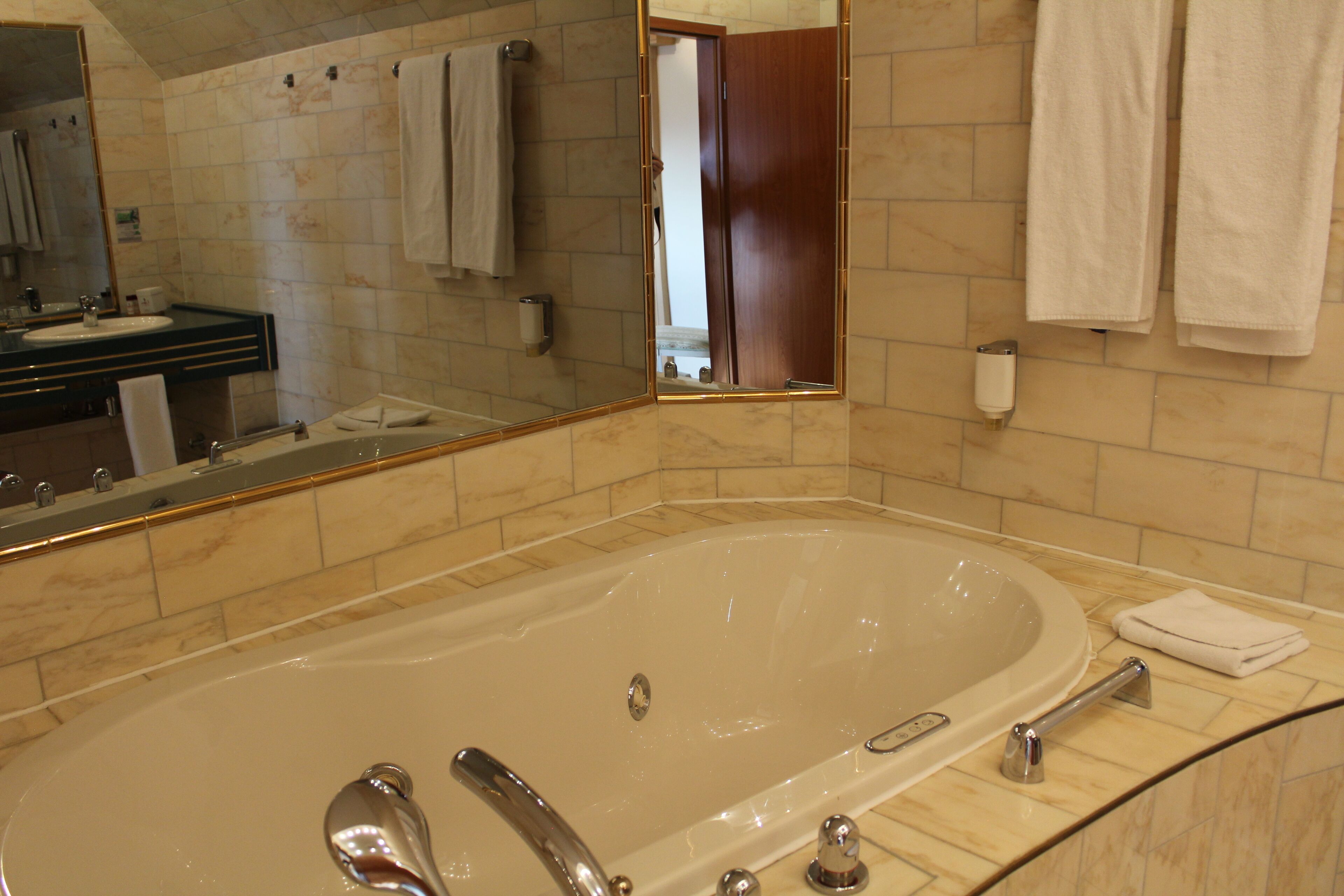 Ein modernes Badezimmer mit einer großen Badewanne, einem Waschtisch inklusive Spiegel und einem Handtuchhalter.