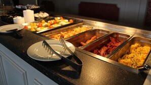 Een buffet met diverse gerechten, waaronder eieren, tomaten en vlees.