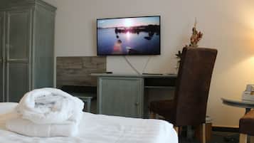 A hotel room with a bed, a TV displaying a sunset over water, a desk, and a chair.