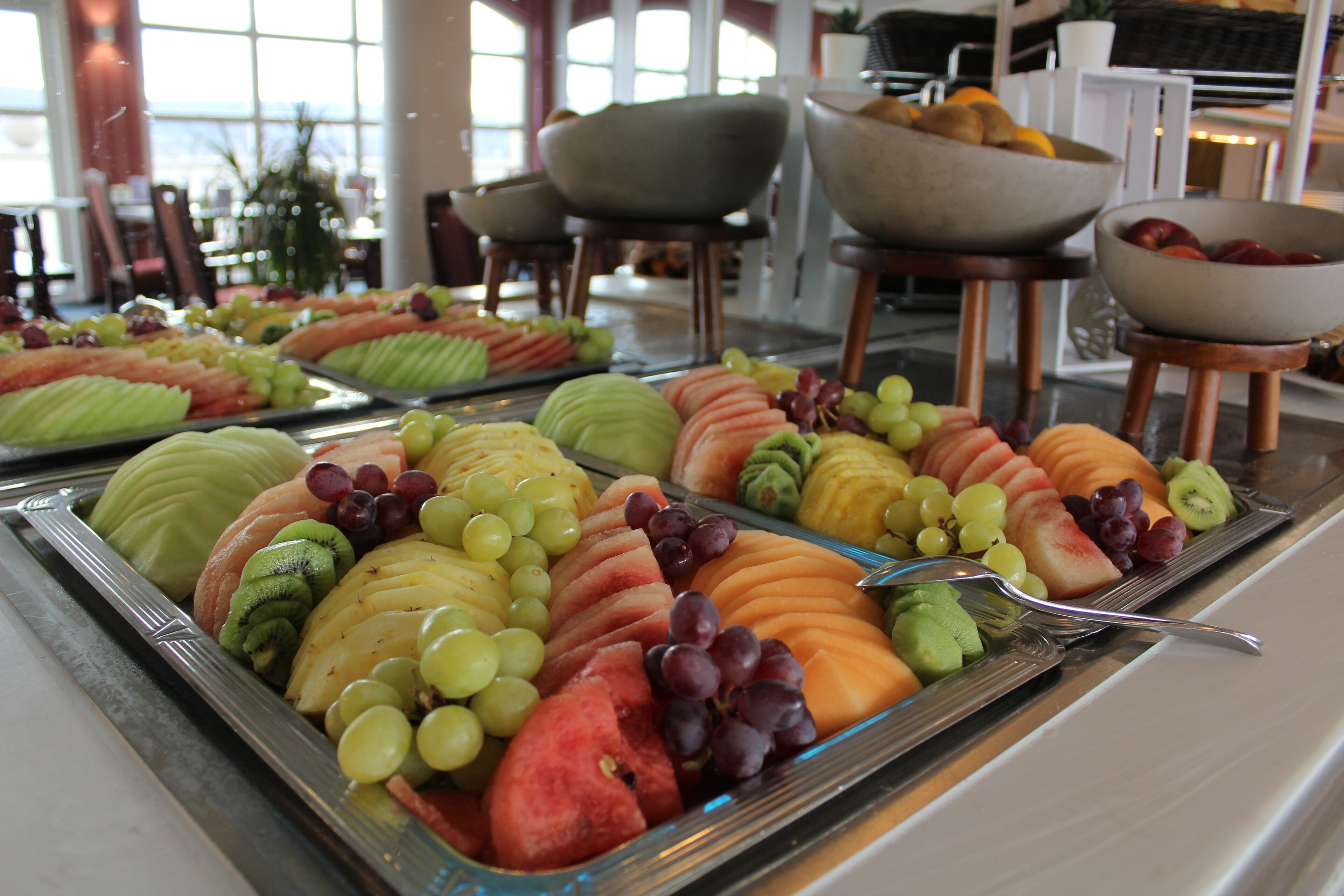 Un buffet proposant une variété de fruits et de légumes présentés sur des plateaux.