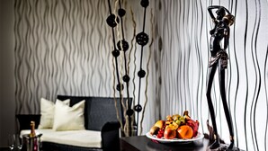 A modern room with a bed, a table with a fruit plate, and a decorative sculpture.
