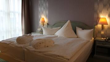 A hotel room with a large bed, two bedside lamps, and a window with curtains.