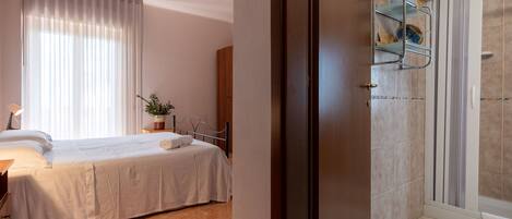 A bedroom with a bed, bedside table, and a window with curtains.