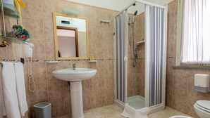 A bathroom with a sink, mirror, shower, and toilet.
