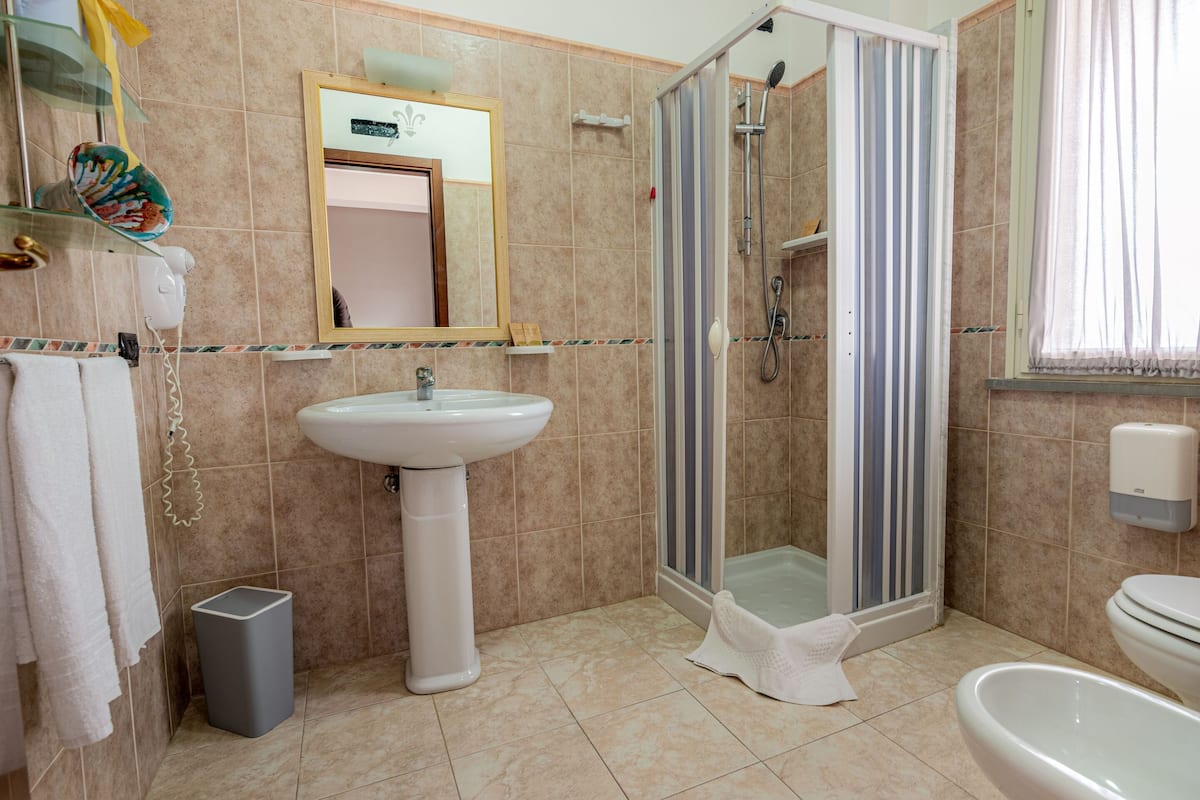 Ein Badezimmer mit Waschbecken, Spiegel, Dusche und Toilette.