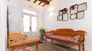 A room with a wooden bench, a chair, a potted plant, and a wall with mirrors.
