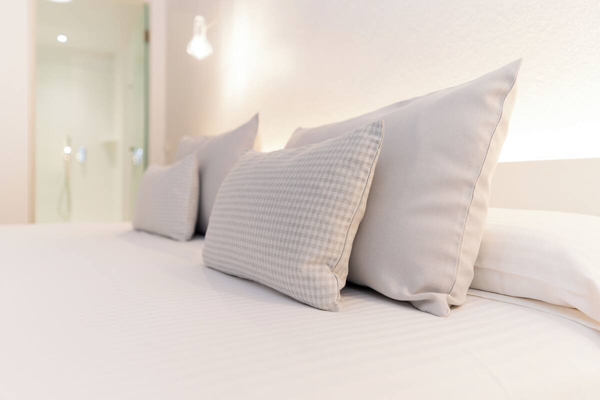 A neatly made bed with multiple pillows and a clean, minimalist design.
