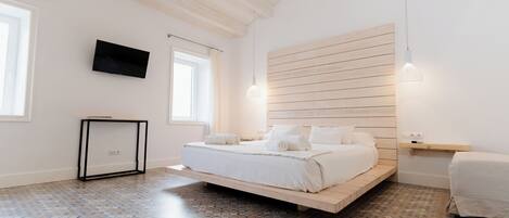 A bedroom with a bed, a TV mounted on the wall, and a wooden headboard.