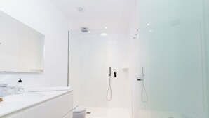 A modern bathroom with a glass shower enclosure, a white sink, and a toilet.