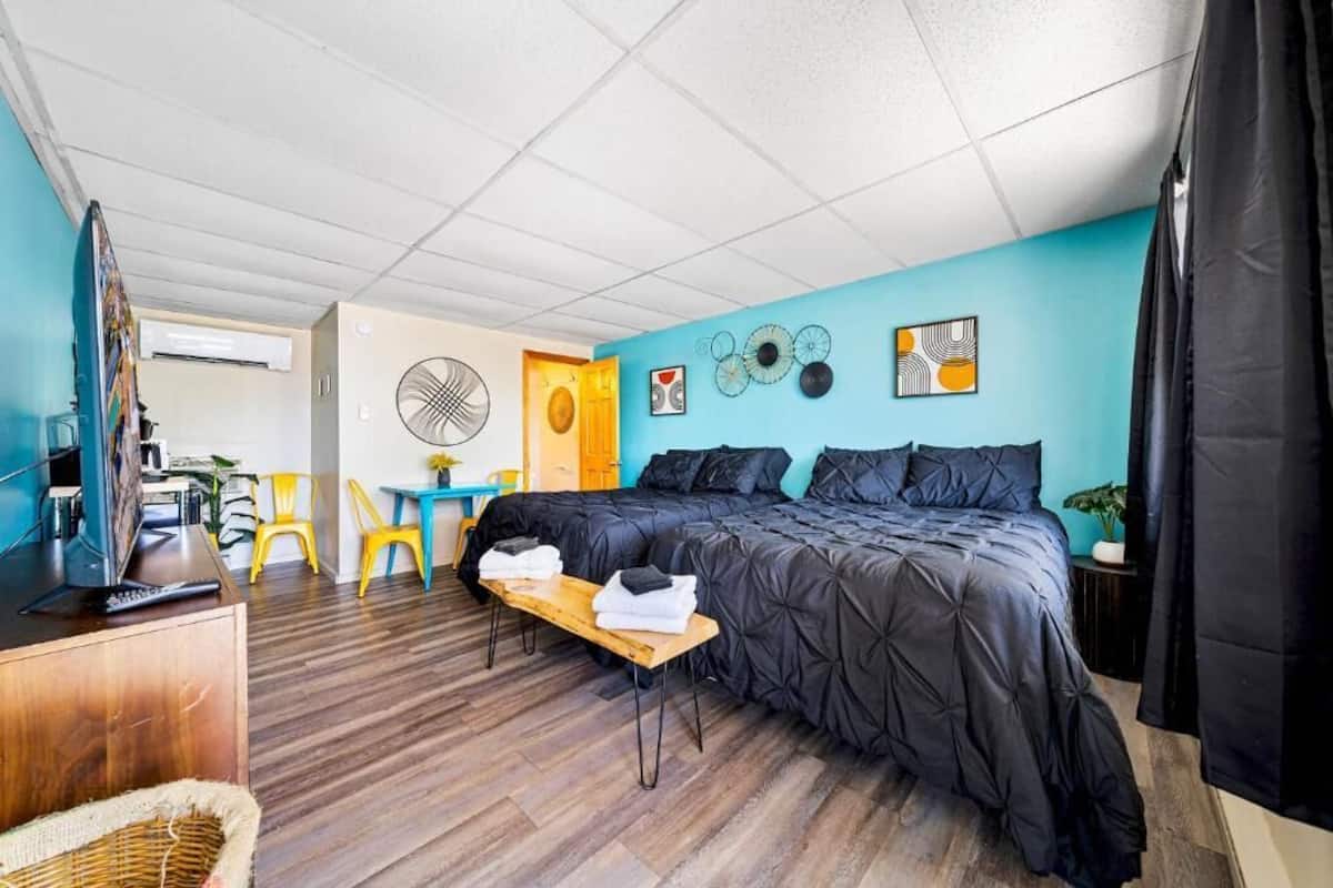 A bedroom with a bed, a desk, a chair, a fan, and a wall with decorative plates.
