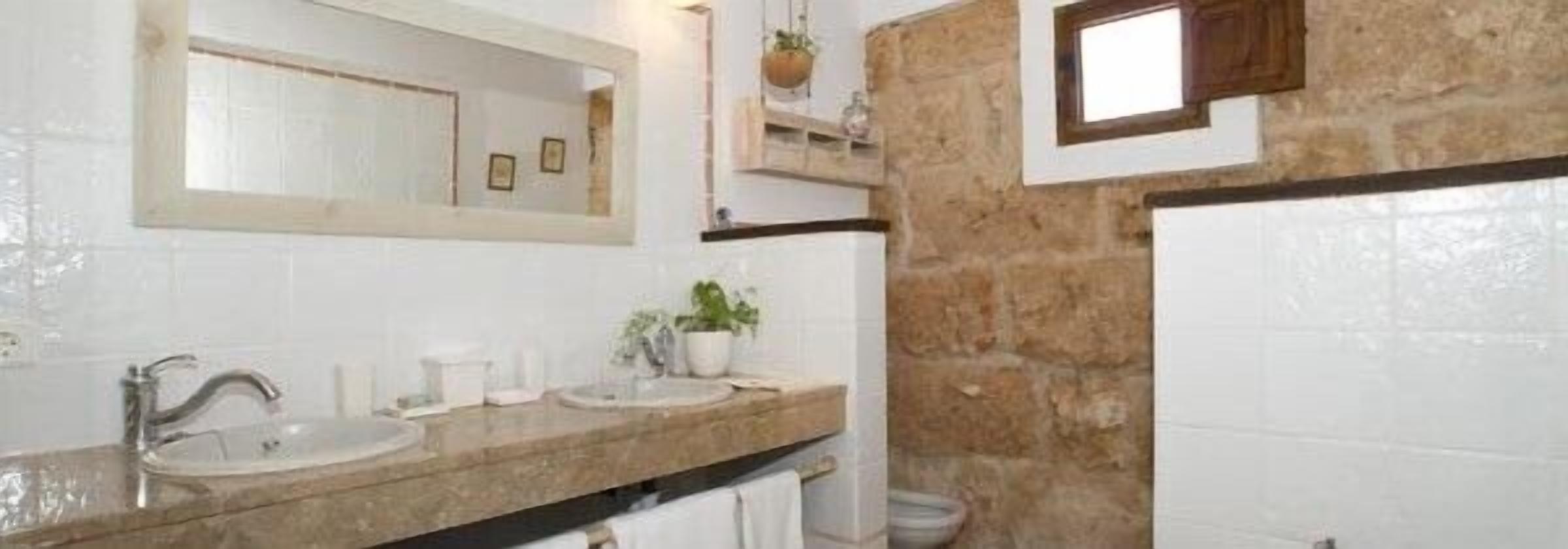 A bathroom with two sinks, a mirror, and a stone wall.