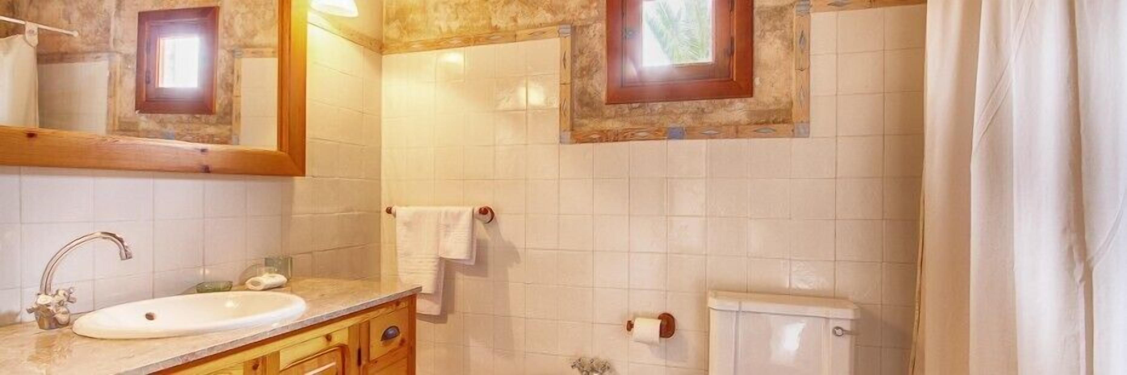 Une salle de bain équipée d’un lavabo, d’un miroir, d’un porte-serviettes, de toilettes et d’une fenêtre.