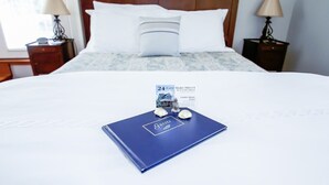 A neatly made bed with a blue guest book, two small decorative items, and a framed picture of a house on the bed. - 24 East Main Street B&B (Canton)