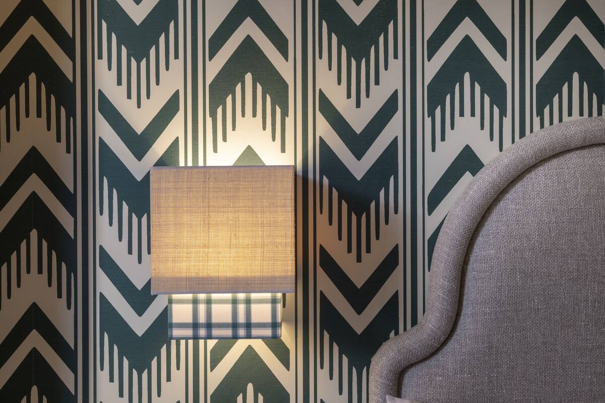 A wall with a geometric pattern and a window with a plaid curtain.