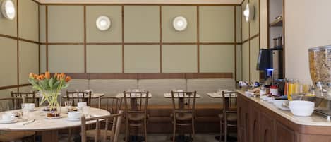 Um restaurante com cabines, mesas redondas e um balcão com uma máquina de café.