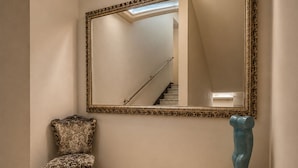 A hallway with a marble floor, a chair, a large mirror, and a sculpture. - Hotel Posta (Cecina)
