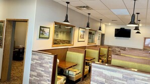 Un restaurante con asientos tipo cabina, detalles de madera y un televisor de pantalla plana en la pared.