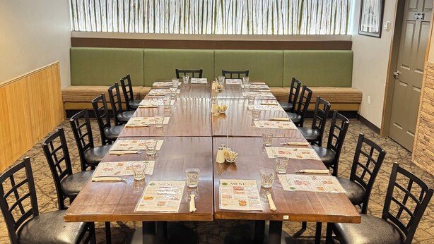 Un salón de conferencias con una larga mesa, sillas y un muro decorativo.
