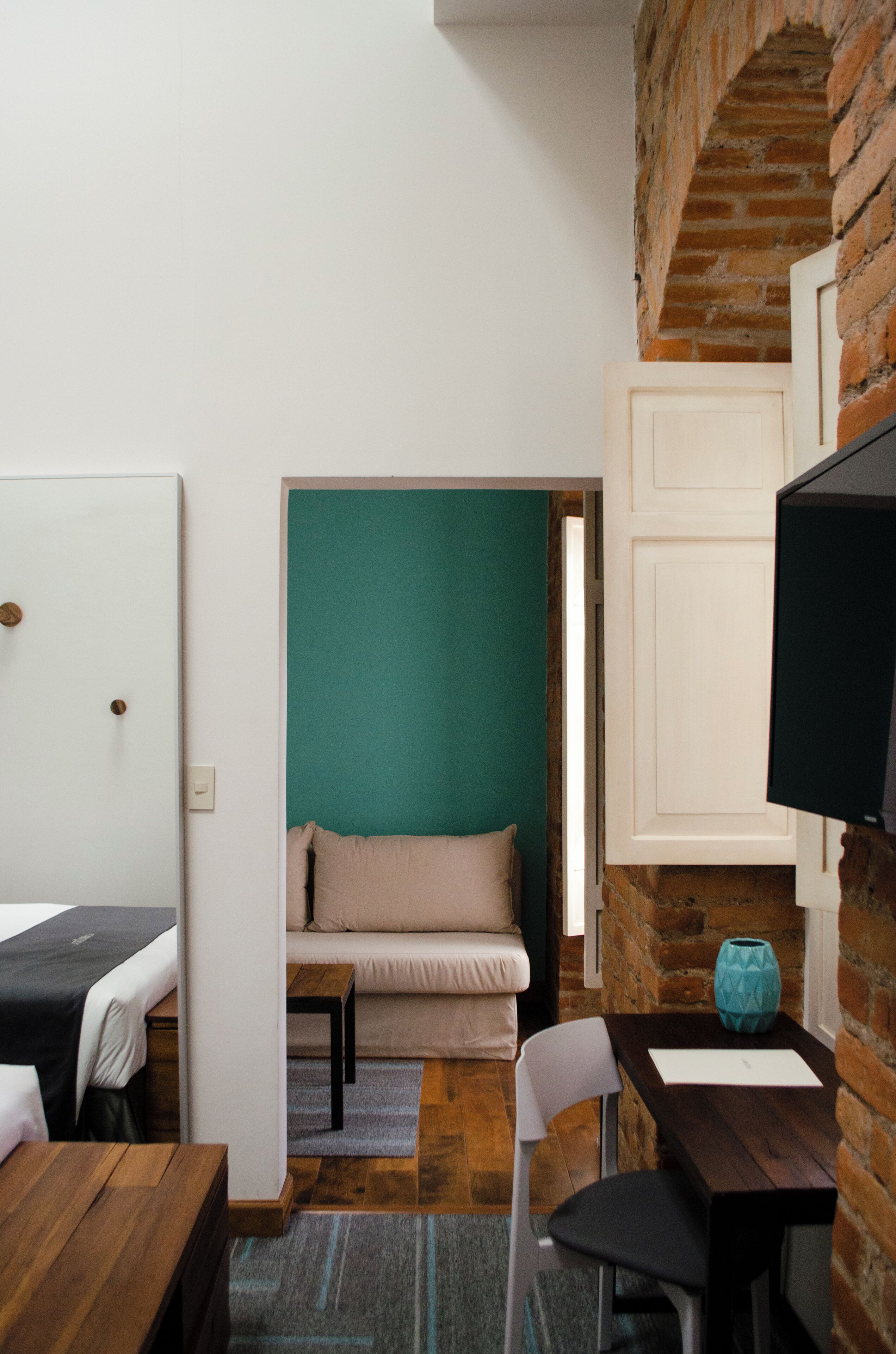 A compact room with a bed, a sofa, a small table, and a television.