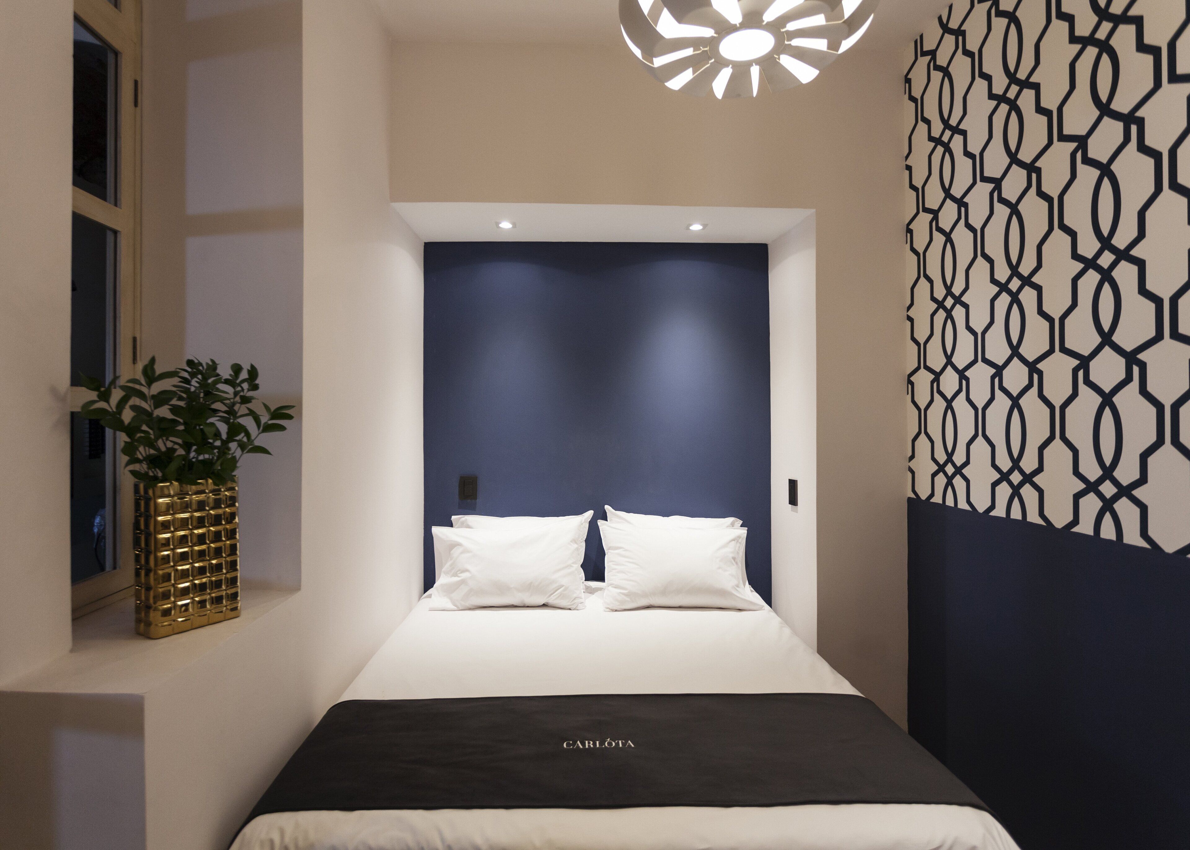 Un dormitorio moderno con un cabecero azul oscuro, ropa de cama blanca y un diseño decorativo en la pared.