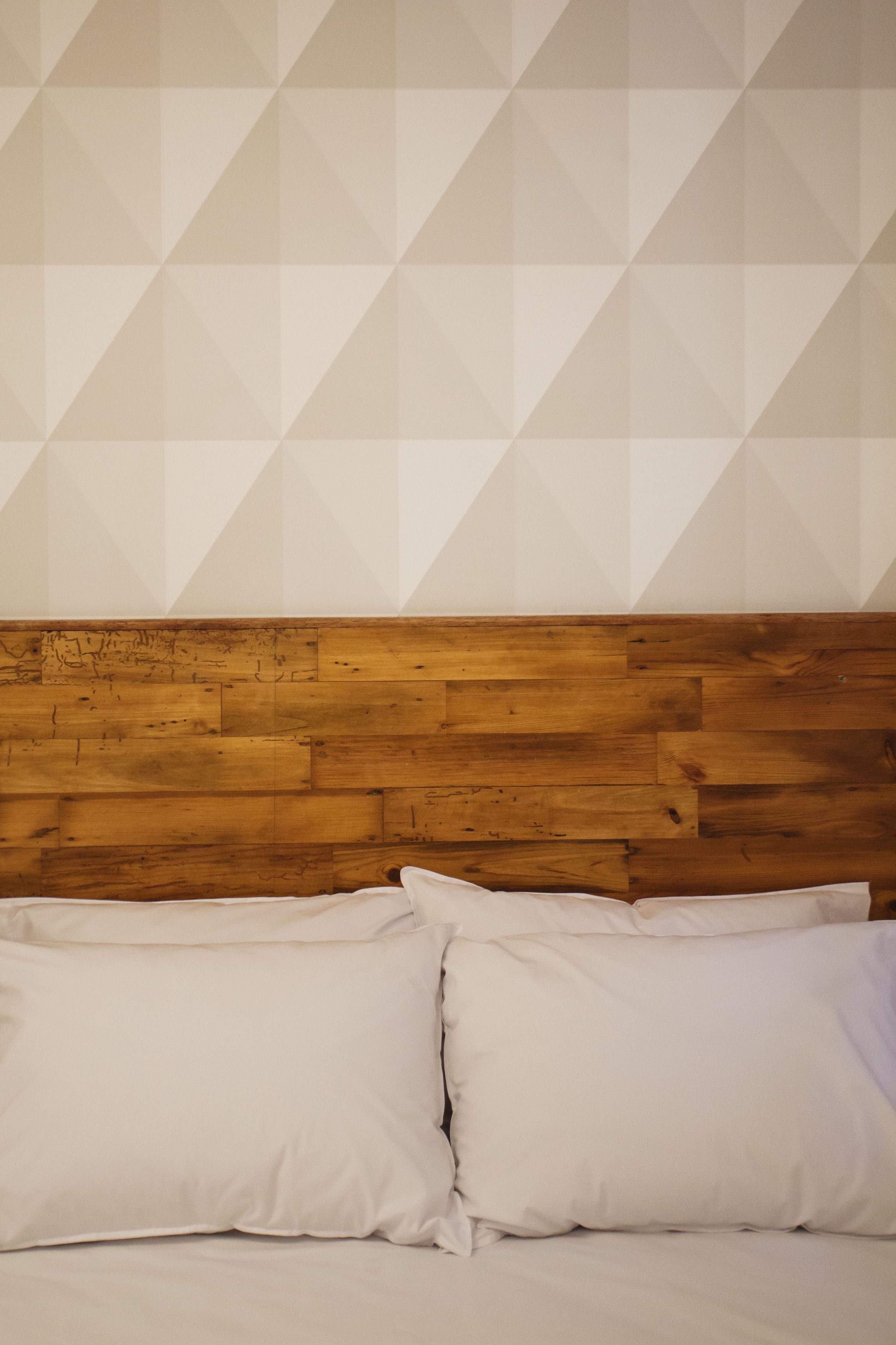 A bed with a wooden headboard and white pillows.