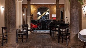 A grand lobby with a piano, stone columns, and a checkered floor. - Carlota Sustainable Design Hotel (Quito)