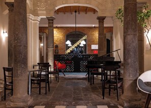 A grand lobby with a piano, stone columns, and a checkered floor. - Carlota Sustainable Design Hotel (Quito)