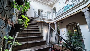 A grand staircase with a metal railing, leading to a balcony with a view of the building's interior. - Carlota Sustainable Design Hotel (Quito)