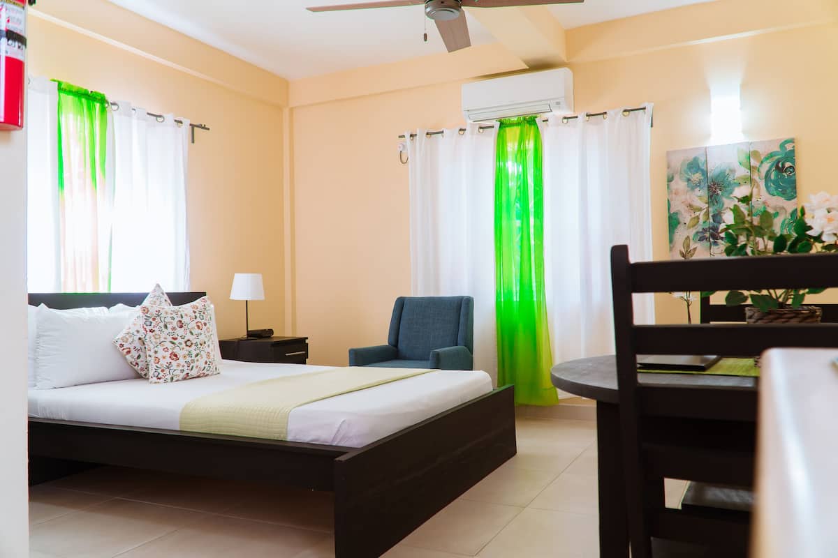 A hotel room with a bed, a chair, a table, and a painting on the wall.