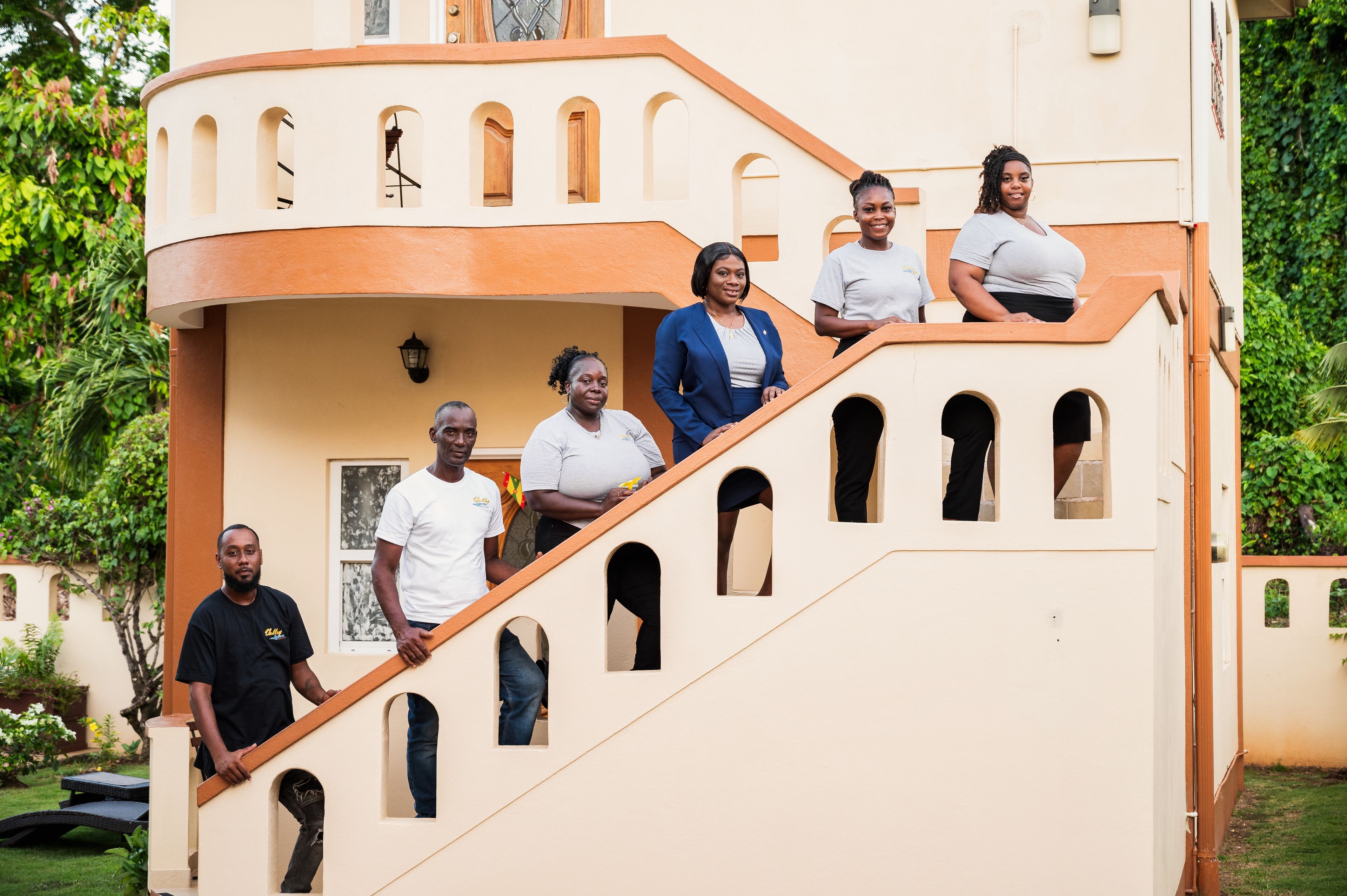 A group of people on a curved staircase with multiple windows, surrounded by greenery.