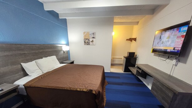 A hotel room with a bed, a TV mounted on the wall, a desk, and a small table. - Budget Inn Winter Haven (Winter Haven)