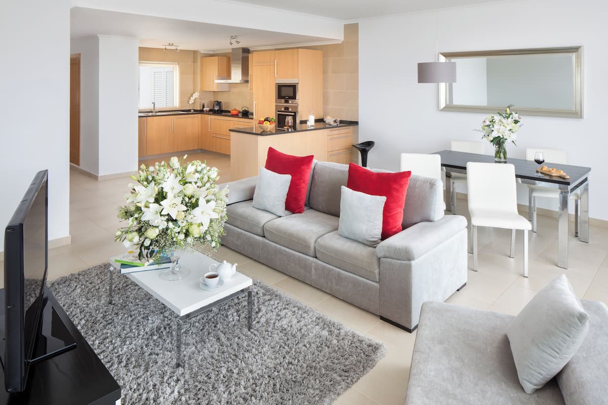 Un salon moderne avec un canapé gris, des coussins rouges et blancs, une table basse et un téléviseur.