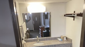 Uma casa de banho pequena com lavatório, espelho e porta-toalhas.