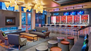 A modern lounge area with seating, a bar, and a view of the city. - Aloft by Marriott Austin Northwest (Austin)